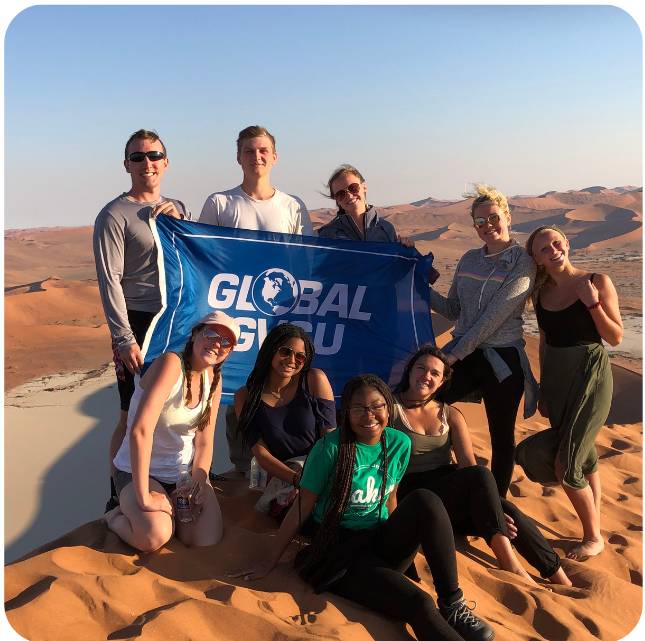 Students in the desert with GVSU flag on study abroad trip to Namibia